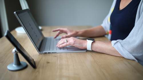 standing desk person in white and blue shirt using macbook pro office